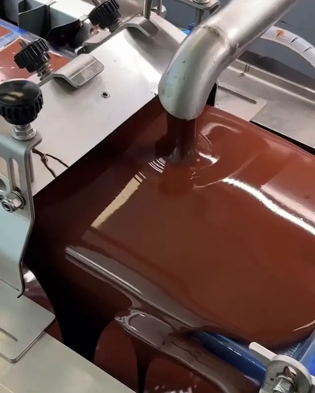 Glossy tempered chocolate flowing in the machine