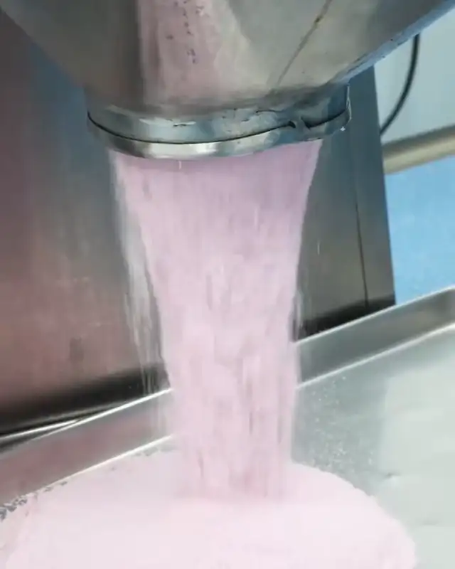 Pink tablet powder pouring from a hopper
